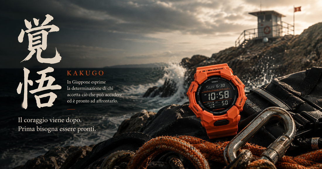 G-SHOCK GD-010-4ER arancione su scogliera mediterranea con torretta di soccorso sullo sfondo, kanji 覚悟 (kakugo) in bianco